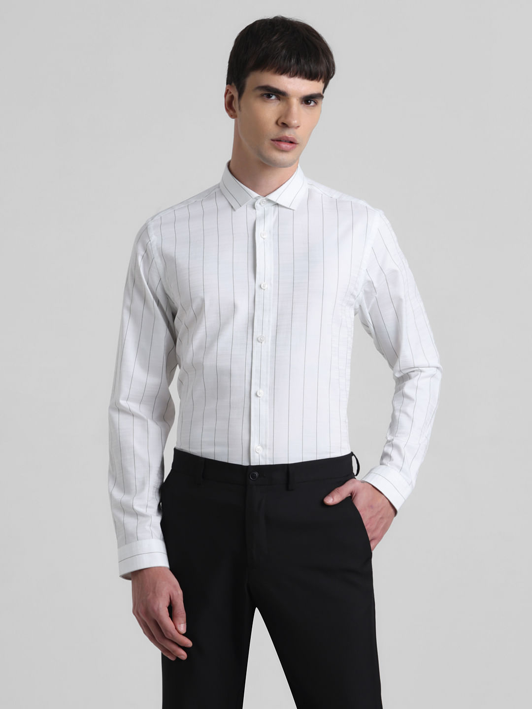 Urban elegant young man with a fashionable hairstyle in a classic black  shirt in a white